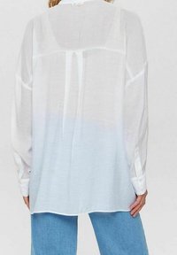 White, semi-sheer, long-sleeve shirt with a relaxed fit, buttoned cuffs, and a subtle gradient effect at the hem. Soft texture.