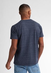 Tricou bleu marin cu mânecă scurtă, cu dungi orizontale texturate, guler rotund și croială lejeră, asortat cu blugi bleu deschis.