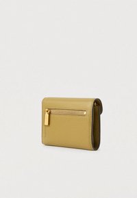 Kompaktowy portfel ze skórki w musztardowym kolorze z teksturowaną powierzchnią, złotą kieszonką na zamek i widocznym uchwytem do zamka z logo.