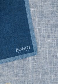 Zila lina kabata ar teksturētu virsmu, apmalē tumšākā zilā krāsā. Stūrī baltā krāsā izceļas „BOGGI MILANO” zīmols.