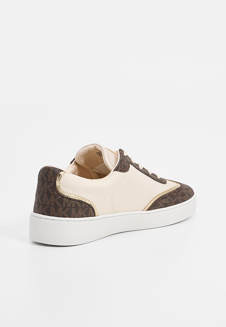 Baskets avec une tige en tissu crème, des accents de monogramme marron et des garnitures en or. Elles présentent une épaisse semelle blanche et une forme arrondie.