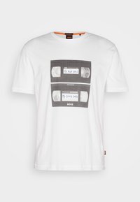Weißes Baumwoll-T-Shirt mit einer Grafik von zwei schwarzen VHS-Kassetten, die blaue Etiketten mit den Aufschriften "MEINE SCHLECHTEN TAGE" und "MEINE GUTEN TAGE" tragen.