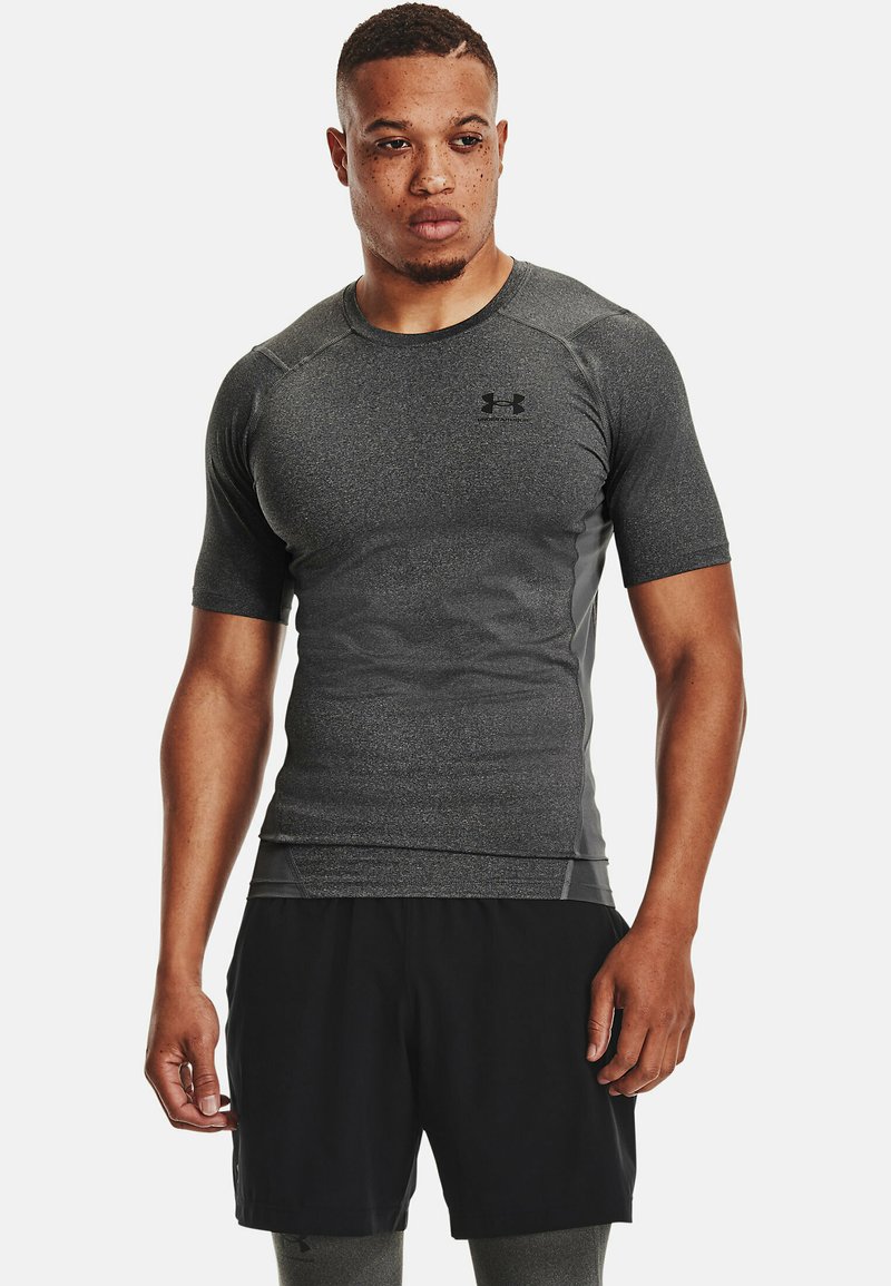 T-shirt de sport noir à manches courtes avec une finition grise texturée. Il présente un col rond et un logo Under Armour sur la poitrine.