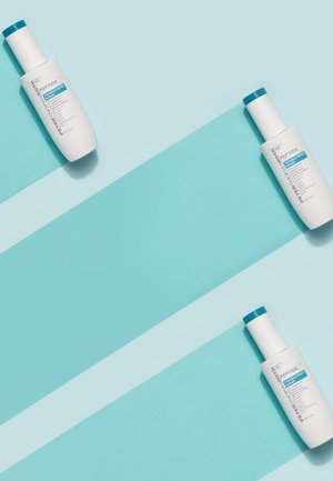 Trois flacons blancs de sérum résistant aux rides Peptide 21 de Peter Thomas Roth disposés en diagonale sur un fond bleu rayé.