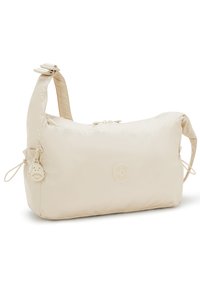 Beige nylon bag with a rounded shape, adjustable strap, and zippered top closure. Features a logo patch and a small smiley keychain detail.