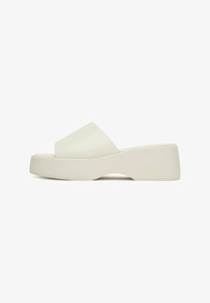 Sandał na platformie w matowej, kremowobiałej kolorystyce, z szerokim paskiem na stopie i wygiętą podeszwą zapewniającą stabilność. Gładka faktura na całej powierzchni.
