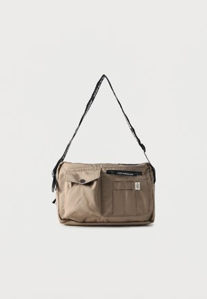 Beige rectangular shoulder bag with multiple front pockets, black zipper, and adjustable black strap with white text.