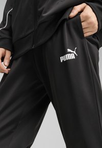 Pantalones deportivos negros de tejido suave con un corte relajado, que presentan un logo blanco de Puma en la pierna izquierda y un bolsillo lateral.