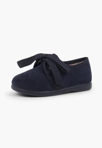 Scarpa in suede blu navy con punta rotonda, cuciture decorative e lacci a fiocco. Il design include una tomaia strutturata e suola piatta.
