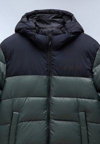 Puffer jacket with a detachable hood, featuring dark navy and green paneling, front zip closure, and two side pockets with a smooth finish.