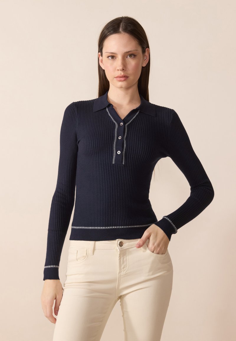 Pull-over à côtes bleu marine avec col, patte de boutonnage à cinq boutons, couture contrastante au niveau des poignets et de l'ourlet, fabriqué à partir d'un tissu doux et texturé.