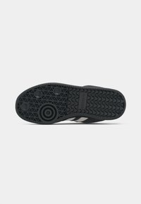 Μαύρη σόλα παπουτσιού με κυκλικά, τριγωνικά και κυματιστά σχέδια πέλματος, με το λογότυπο της Adidas κοντά στο κέντρο.