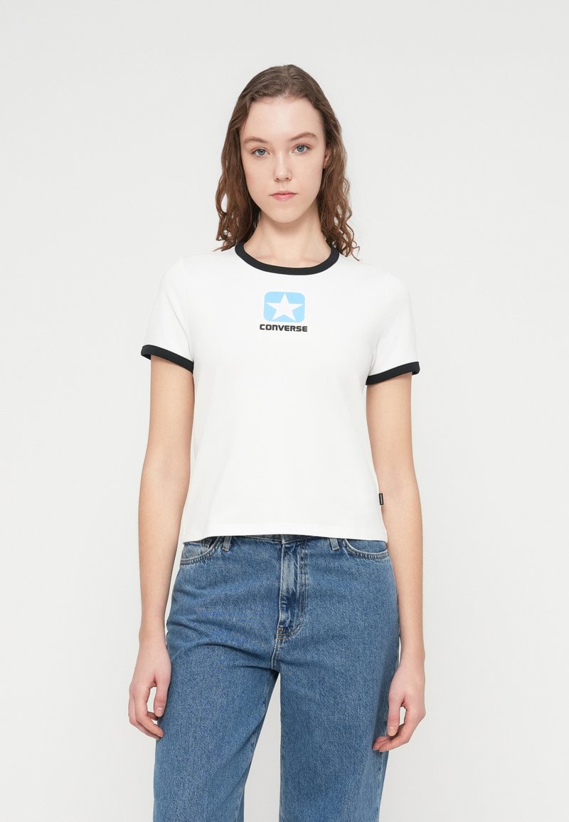 Λευκό κοντομάνικο μπλουζάκι με μαύρες μανσέτες και λαιμόκοψη. Διαθέτει μπλε λογότυπο αστέρι και το κείμενο "CONVERSE" στο κέντρο του στήθους.