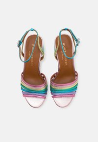 Sandali con cinturini colorati a strisce arcobaleno, con una base rosa lucida, cinturini multicolori texture e una finitura metallica. Presentano una cinghia alla caviglia con fibbia.