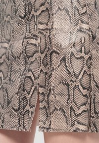 Gonna skinny, di lunghezza al ginocchio, con motivo in stampa serpente in colori beige e nero. Presenta una fessura laterale e una texture liscia.