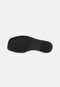 Svart gummisula med en plan, slät yta, rundad tå och detaljerad hälområde. Minimalistisk design utan synliga mönster eller accenter.