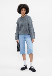 Pilkos megztos suknelės su kaspinu akcentais, šviesiai mėlynos džinsinės bermudos šortai, juodos platformos bateliai, balti kulkšninius kojines ir juoda studded rankinė.