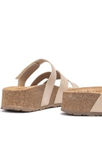Sandales à plateforme en daim beige avec semelles en liège, présentant une forme courbée et un design à brides croisées pour un maintien sécurisé. Semelle texturée pour une meilleure adhérence.