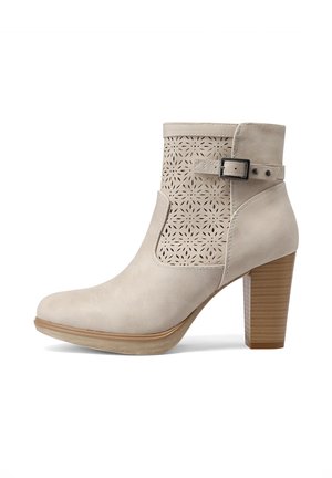 Stivaletto beige alla caviglia con motivo floreale traforato al laser, cinturino laterale con fibbia e tacco a blocco in legno impilato su sfondo bianco.