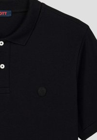 Polo shirt nera con tessuto testurizzato, tre bottoni bianchi e un'etichetta in gomma nera sul lato sinistro del petto. Presenta un colletto classico.