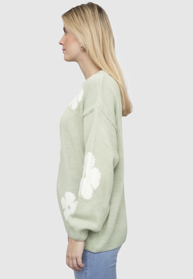 Mintrohelene kootud kampsun valgete lillemustritega, ümmargune kaelus, langeva õlaga ning soonikkäiste ja -äärtega.