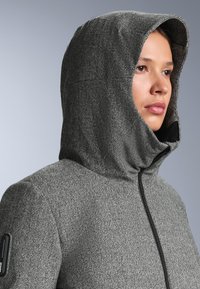 Mikina s kapucňou v houndstooth vzore, šedá a čierna, s plným zipsom a jemne textúrovanou látkou. Obsahuje priliehavú kapucu.