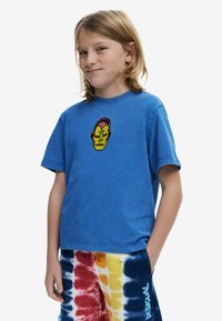 Blue cotton t-shirt with a round neckline and short sleeves, featuring a colorful embroidered face design on the chest.