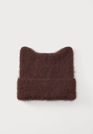 Bonnet en maille douce marron foncé avec des pointes ressemblant à des oreilles de chat, présenté sur un fond clair uni.