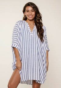 Top kaftano a righe in azzurro chiaro e bianco, realizzato in tessuto leggero. Presenta un collo a V, maniche ampie e una vestibilità rilassata con spacco laterale.