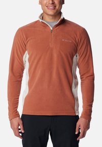 Fleece-Pullover in rostorange mit einem Viertel-Reißverschluss, cremefarbenen Seiteneinsätzen und dezentem Logo auf der linken Brust. Weicher Stoff und lange Ärmel.
