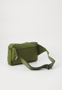 Green, rectangular bag with a textured fabric, adjustable strap, front zip pocket, and flat design for compact storage.