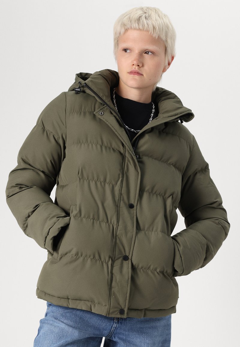 Chaqueta tipo puffer de color verde oliva, con costuras horizontales, capucha, bolsillos frontales y cierre de botones. Textura suave con un corte holgado.