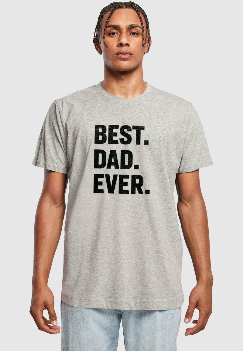 Camiseta de algodón gris con texto negro en negrita que dice "MEJOR. PAPÁ. DE TODOS LOS TIEMPOS." Diseñada con mangas cortas y un cuello redondo.