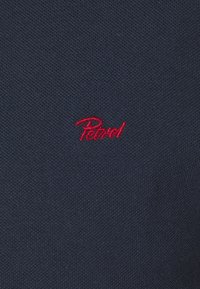 Navyblauwe textuurstof heeft een opvallend rood geborduurd logo "Patrol" aan de linkerkant. Eenvoudig, casual ontwerp voor veelzijdig gebruik.