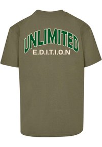 Oliven grøn kortærmet t-shirt med stor hvid og grøn tekst på ryggen, som siger "UNLIMITED E.D.I.T.I.O.N." i fed skrift.