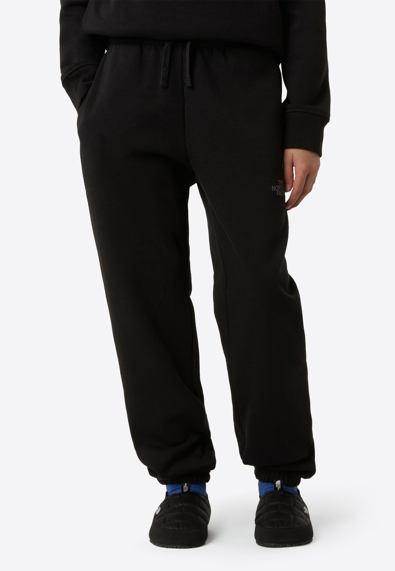 Pantalones deportivos negros con un ajuste relajado, que cuentan con una cintura elástica con cordón. Detalle de logotipo notable en el muslo izquierdo. Textura de tela suave.