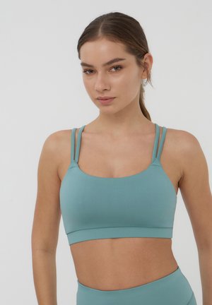 Jasnoniebieski biustonosz sportowy wykonany z elastycznej tkaniny. Posiada cienkie podwójne ramiączka i szeroki pas pod biustem. Gładka faktura, minimalistyczny design.