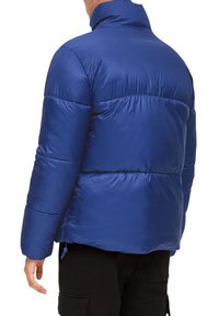 Blauwe gewatteerde jas met hoge kraag, gestikte textuur en zijzakken, ontworpen voor warmte en comfort, met elastische manchetten.