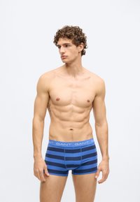 Modri in mornarsko modri boksarji z mehkobo teksturo, z elastičnim pasom z logotipom. Dizajn poudarja udobje in prilegajočo se obliko.