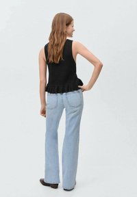 Črn rebrast top s peplum robom, v kombinaciji s svetlobluzimi širokimi kavbojkami, ki imajo zadnje žepe in gladko denim teksturo.