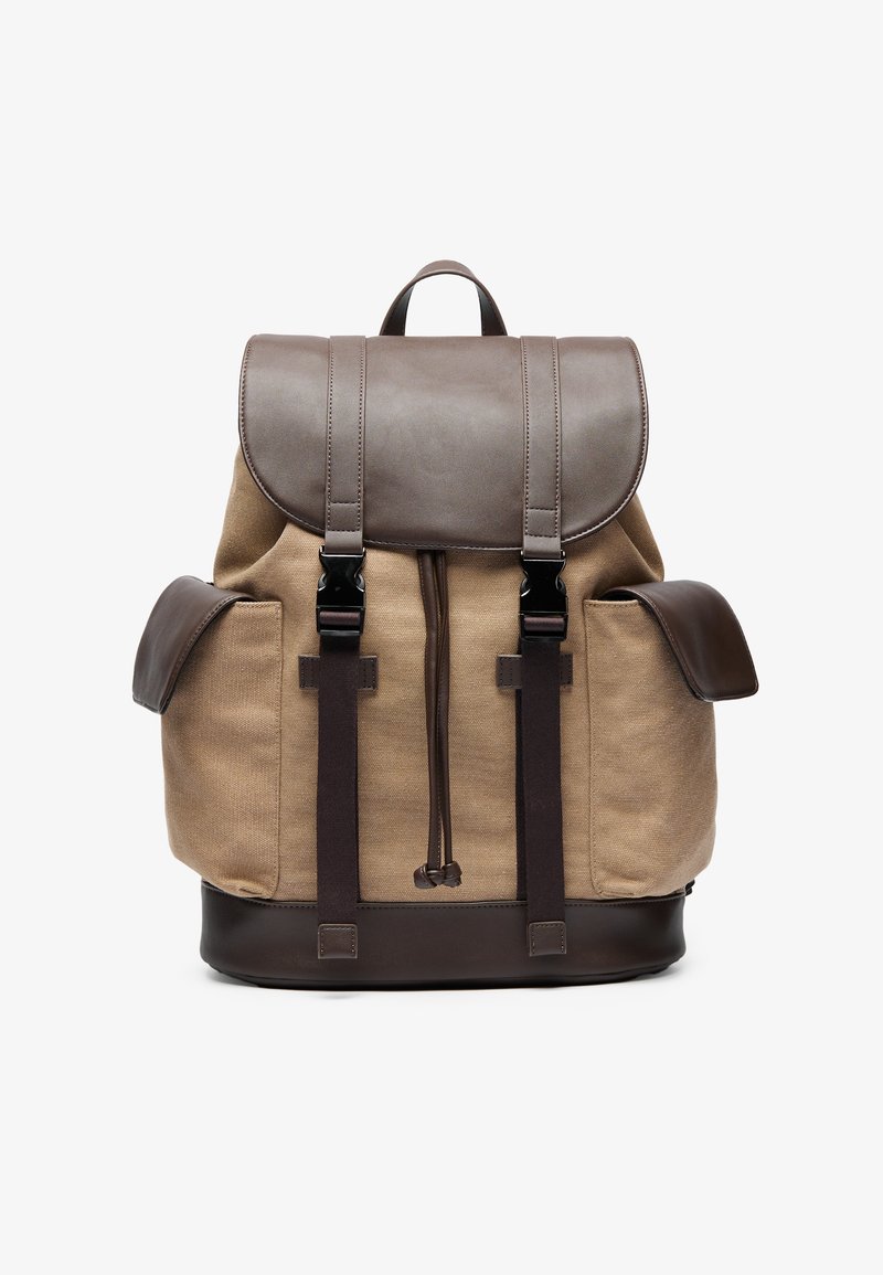 Zaino in tela di colore beige con dettagli in pelle marrone. Presenta un coperchio superiore, spallacci regolabili e due tasche laterali. Forma rettangolare, design robusto.