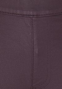 Leggings morados hechos de una tela suave y elástica. Las características incluyen costuras visibles y un diseño ajustado y elegante.