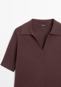 Bordeaux kortærmet polo sweater med V-hals og flad krave, lavet af blødt stof med en glat tekstur. Etiketten synlig indeni kraven.