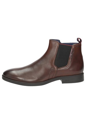Bottine en cuir brun avec panneau élastique, bout arrondi et semelle texturée. Équipée d'une lanière de boucle pour un enfilage facile.