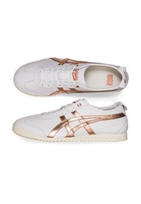 Scarpe da ginnastica bianche con accenti in oro rosa, parte superiore in pelle, dettagli testurizzati e suola in gomma. Presentano lacci classici e un marchio.