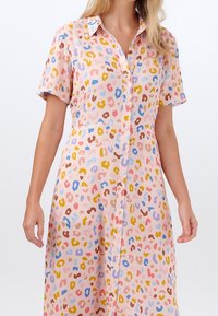 Raitapaita-mekko vaaleanpunaisena, jossa on monivärinen abstrakti leopardi-kuvio, napitettava etuosa ja rento siluetti.