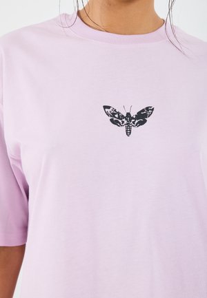Helles rosa Baumwoll-T-Shirt mit einem schwarzen Motten-Graphic zentral auf der Brust. Kurze Ärmel und ein Rundhalsausschnitt. Glatte Textur.