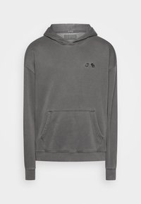 Harmaa hupullinen collegepaita, jossa on etutasku, resorit hihansuissa ja pehmeä materiaali. Edessä kaksi mustaa koristeellista yksityiskohtaa rinnassa.