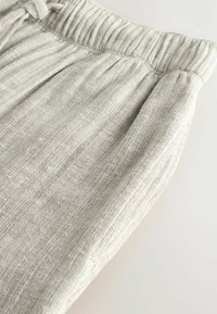 Pantaloni din in gri deschis cu un aspect texturat, având un talie strânsă și pliuri subtile, evidențiind un material moale și respirabil.