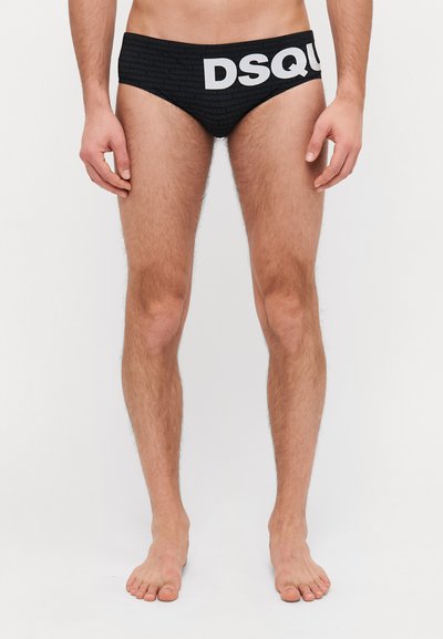 Slip da nuoto neri realizzati in tessuto morbido, con un audace logo DSQUARED2 bianco che attraversa l'elastico in vita, design a vita bassa con vestibilità aderente.